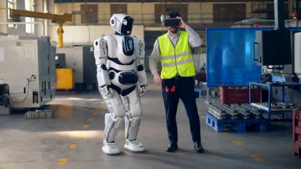像人一样的机器人在一名戴着Vr眼镜的工人之后正在移动 — 图库视频影像