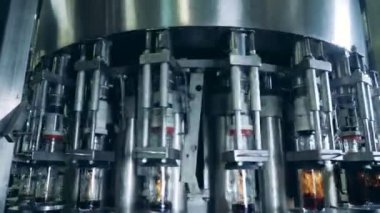 Konveyördeki cam şişeler koyu renk alkolle doluyor.