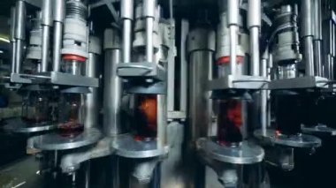 Rotating conveyor is pouring alcohol into glass bottles