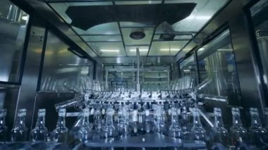 Metal bir makine tarafından taşınan cam şişeler ile fabrika ünitesi