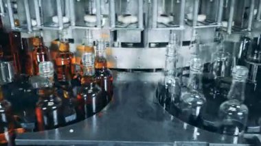 Fabrika makinesi tarafından şişelere alkol dökülüyor.
