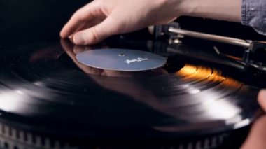 Bir kişi oyuncu üzerine bir vinil kayıt koyarak