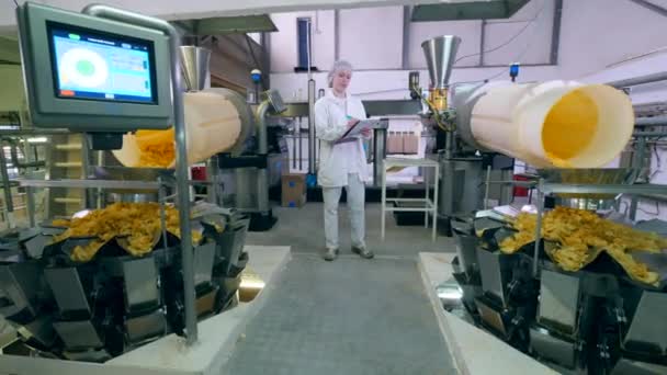 Aardappelchips gieten van machines die door een dame werker worden waargenomen — Stockvideo