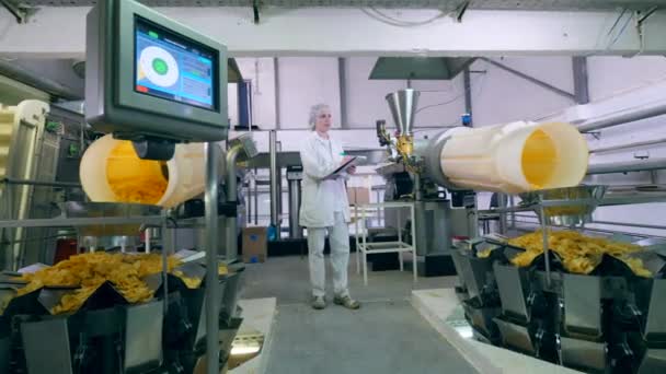 Леди-техник осматривает оборудование, выпускающее чипсы — стоковое видео