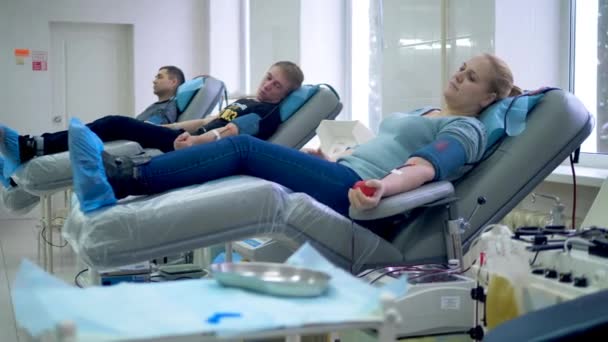 As pessoas estão doando sangue enquanto estão deitadas em poltronas médicas — Vídeo de Stock