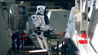 Fabrika makineleriyle çalışırken tabletüzerinde robot tipleri.