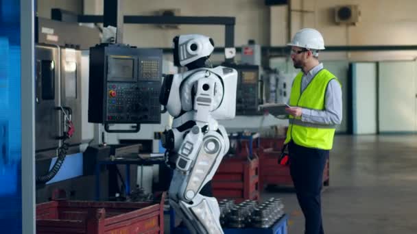 Factory worker controls a droid, uses a tablet. — Stock Video