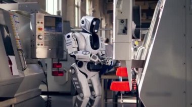 Biyonik robot fabrika ekipmanlarını kontrol eder, tablete yazarak.