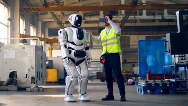 Ingeniero masculino lleva gafas VR y controla un cyborg . — Vídeo de stock