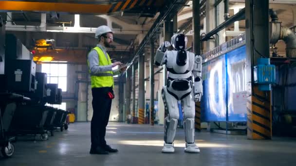 Engenheiro profissional controla um robô, digitando em um tablet . — Vídeo de Stock