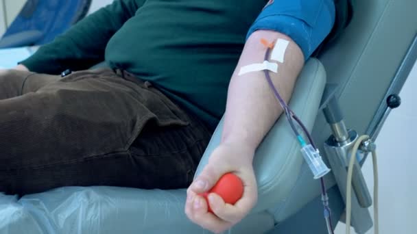 Um homem está deitado em uma cadeira e fazendo uma doação de sangue — Vídeo de Stock