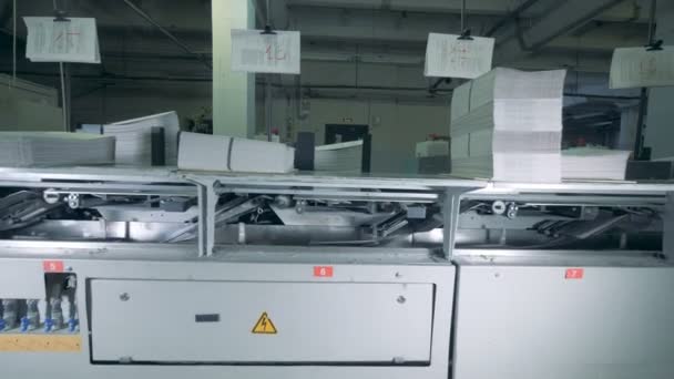 Bedruckte Papierstücke bewegen sich durch eine Druckerpresse — Stockvideo