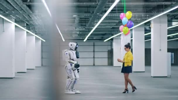 Jongedame geeft kleurrijke ballonnen aan een robot — Stockvideo