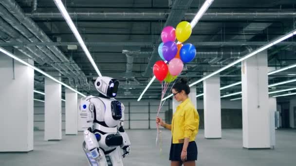 Uma menina e um robô estão segurando balões juntos — Vídeo de Stock