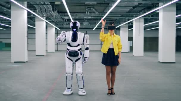 Молодая женщина в VR-очках и робот движутся вместе — стоковое видео