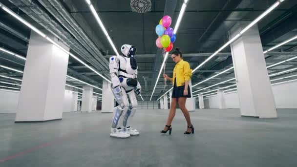 年轻的女人正在把气球送给一个高大的机器人 — 图库视频影像