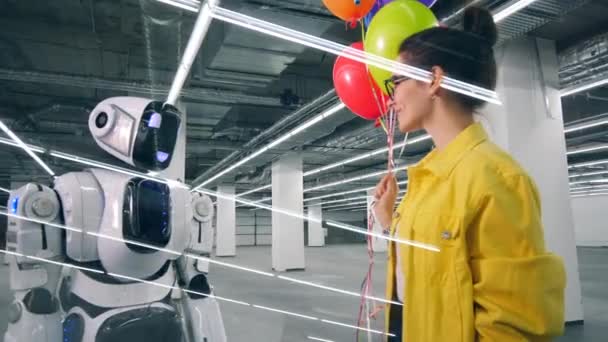 Leende kvinna ger ballonger till en lång Cyborg — Stockvideo