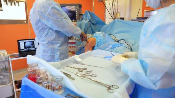 Chirurg i asystent wykonują operację, wykorzystując nowoczesne narzędzia medyczne. — Wideo stockowe