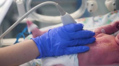Çocuk doktoru bebeklerin kalbini kontrol etmek için bir tarama makinesi kullanıyor.