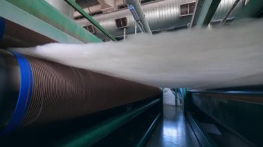 Haddeleme konveyörü üzerinde hareket eden sentetik kumaş tabakası.
