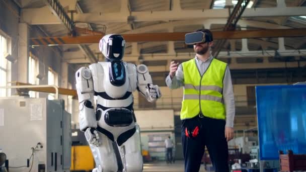 Roboten gjentar bevegelser etter en mann i VR-briller – stockvideo