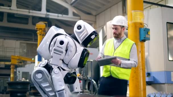 Mannlig ingeniør kontrollerer bevegelsene til en robot – stockvideo