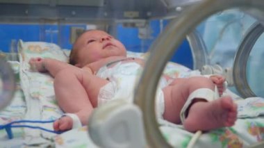 Bebek bezindeki bebek kuvözde yatıyor.