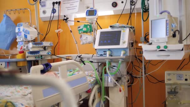 Hospital room filled with equipment and a child lying on a bed — Stock Video