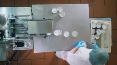 Kadın otomatik taşıyıcı ile çalışıyor, kuru ekmeklerle plastik kaplar seçiyor..