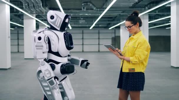 Menina com tablet controla um cyborg, digitando em seu painel . — Vídeo de Stock