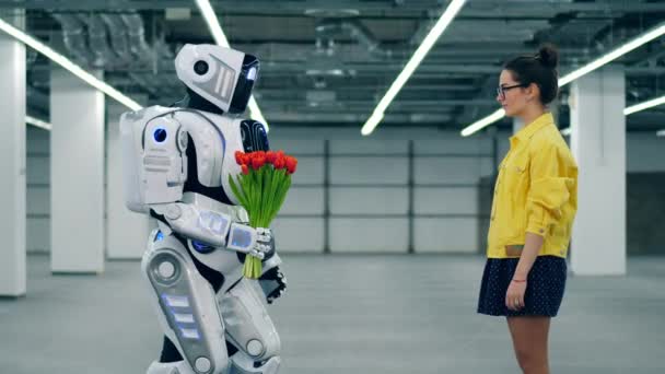 Cyborg geschenken tulpen aan een lachende jonge vrouw, staande in een kamer. — Stockvideo