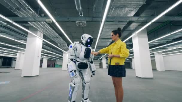 Μια γυναίκα με tablet αλλάζει σε ένα ρομπότ, ελέγχοντας το. — Αρχείο Βίντεο