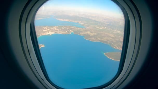Παράθυρο αεροσκάφους με νερό και νησιά που βλέπουν από αυτό — Αρχείο Βίντεο