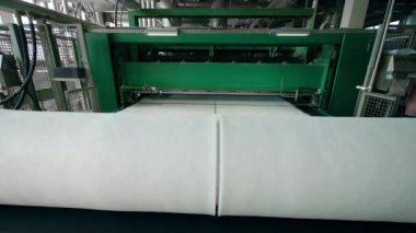 Polyester vuruş çalışan bir konveyör üzerinde büyük bobinler içine haddelenmiş.