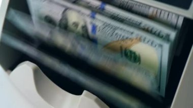 Sayım ekipmanında hareket eden, bankada kontrol edilen basılı dolarlar.