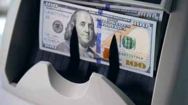 Özel bir bankacılık makinesinde sayılan dolar yığını.