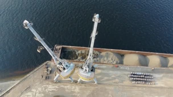 Les grues modernes travaillent sur les quais, déplaçant les pierres de rupture d'une péniche .