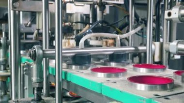 Fabrika makinesi folyo ile kapları kaplar. Gıda fabrikası ekipmanları.