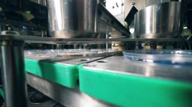 Endüstriyel mekanizma ekmek kırıntılarını kaplara döküyor. Gıda fabrikası ekipmanları.
