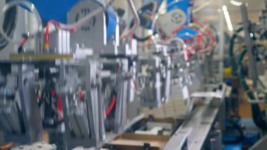 Modern fabrika ekipmanları. Robotik mekanizma karton kutuların yerini değiştiriyor ve paketliyor