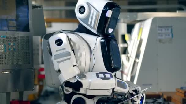Människa-liknande Droid är att driva en tablett i en fabriks enhet — Stockvideo