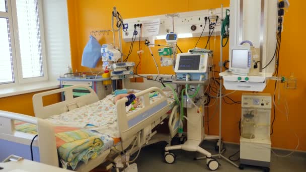 Sprzęt szpitalny działa w oddziale, podczas gdy dziecko śpi w łóżku. — Wideo stockowe