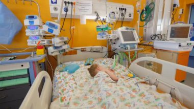 Küçük hasta hastane koğuşunda bir yatakta uyur.