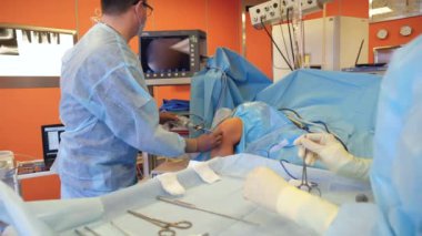 Erkek cerrah bir hasta diz ile çalışırken kamera ile bir araç kullanır.