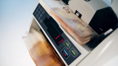 Bir adam euro banknotlarını kontrol etmek için para sayacı kullanıyor..