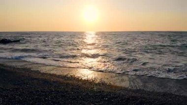 Gün batımı ve okyanus dalgaları kıyı boyunca koşuyor
