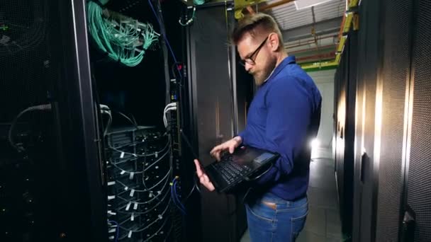 Experto masculino está operando un ordenador portátil enchufado — Vídeos de Stock