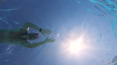 Bir turist büyük bir havuzda, gözlük takarak yüzer..