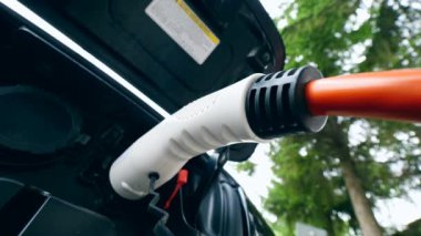 Adam şarj kablosunu elektrikli araba prizinden çıkarır. Elektrikli otomobilin şarj edilmesi.