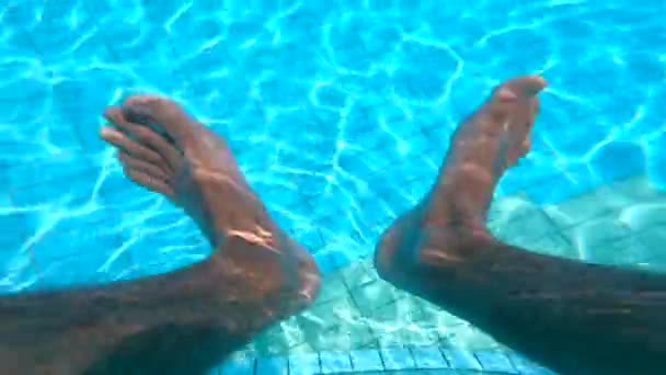 Egy ember lógó lábát egy medencében vizet. A nyári szabadságolási koncepció. — Stock videók
